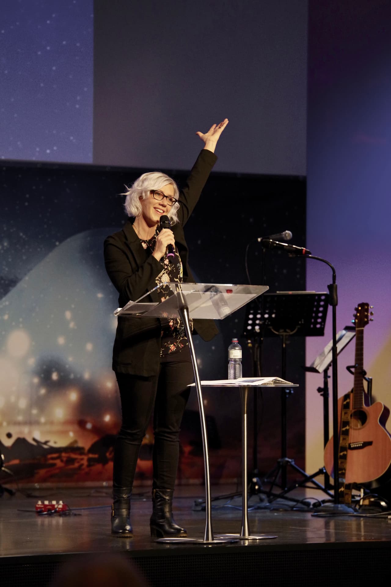 Ruth Truttmann speaking on stage with a raised hand