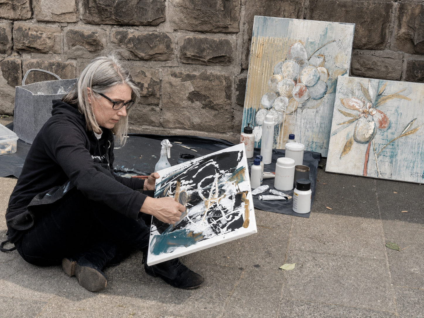 Ruth Truttmann painting outdoors beside finished canvases